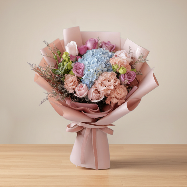 A beautifully arranged bouquet of blue hydrangeas, pink, and white flowers in a pink paper with a ribbon