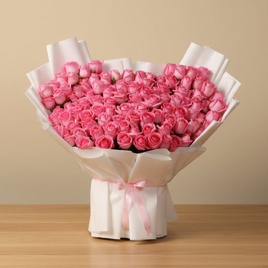 Bouquet of 100 pink roses wrapped in white paper with a pink ribbon