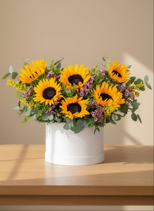 This arrangement is made of Sunflowers, eucalyptus, and pink wax flowers presented in our signature white flower box.