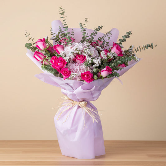 Bouquet of pink flowers wrapped in purple paper