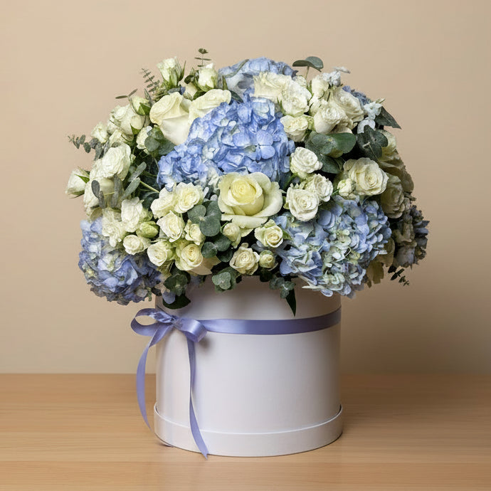 Floral arrangement with blue hydrangea and white roses in a white box