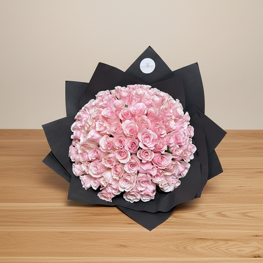 A bouquet of pink roses arranged neatly with black wrapping paper