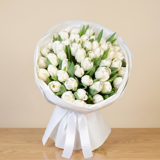 Bouquet of white tulips wrapped in white paper with a ribbon