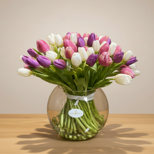 A vase with a mixed color tulip arrangement, featuring shades of white, pink, and purple.